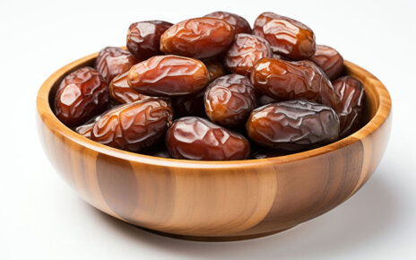 Dates in a wooden bowl on a white background