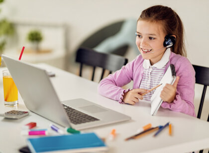 Happy little girl having online class with a teacher over laptop
