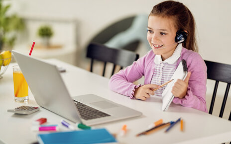 Happy little girl having online class with a teacher over laptop